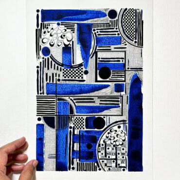 The image features a person’s hand holding an abstract art print with a geometric design. The artwork is composed of black and blue shapes, including lines, circles, and rectangles, arranged in a structured yet complex pattern. The design blends solid blue sections with black lines and dots, creating a dynamic and visually engaging composition.