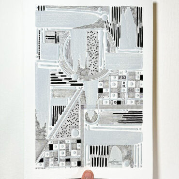 A hand holding an intricate black-and-white abstract artwork featuring various geometric shapes, patterns, and textures, with some areas highlighted in light gray.